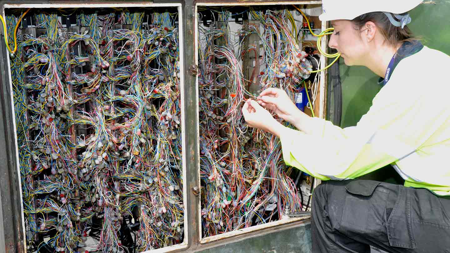 Woman in protective clothing adjusting some wires for broadband
