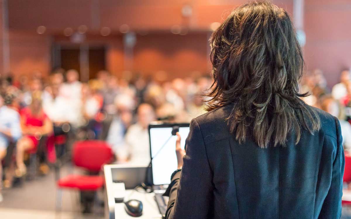 Woman standing at lectern addressing a room